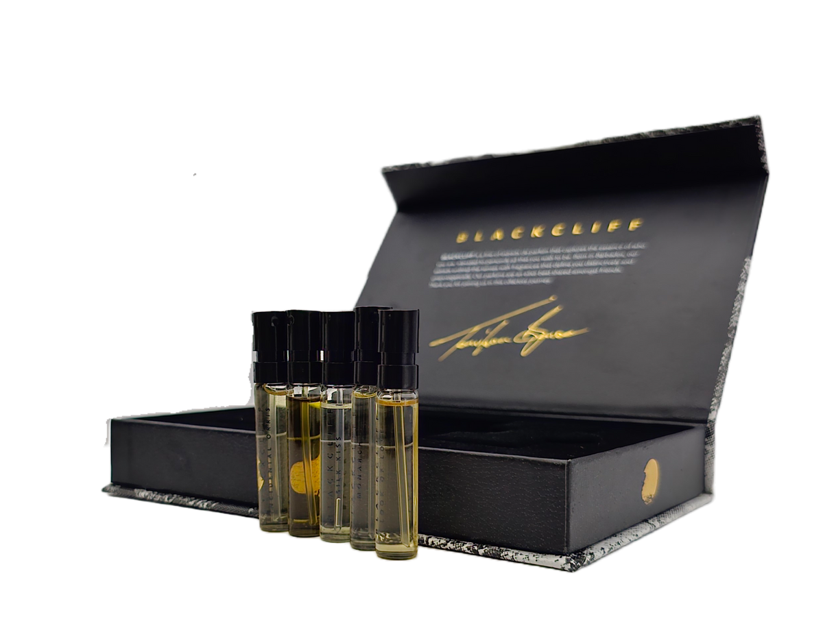 Mini fragrance bottles beside open black box with gold logo